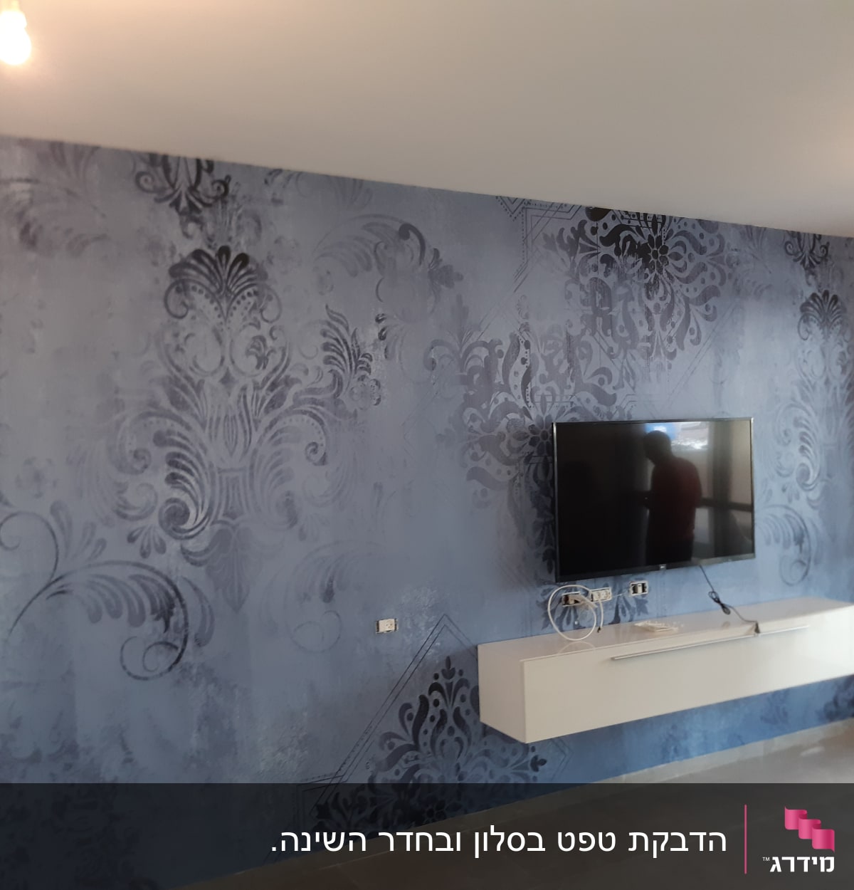 קיר כחול עם דוגמאות דקורטיביות וטלוויזיה תלויה